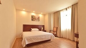 A hotel room with a large bed, a wooden headboard, a painting on the wall, a desk, and a chair. - Pebble Motel (Shanghai Beidi Road) (Shanghai)