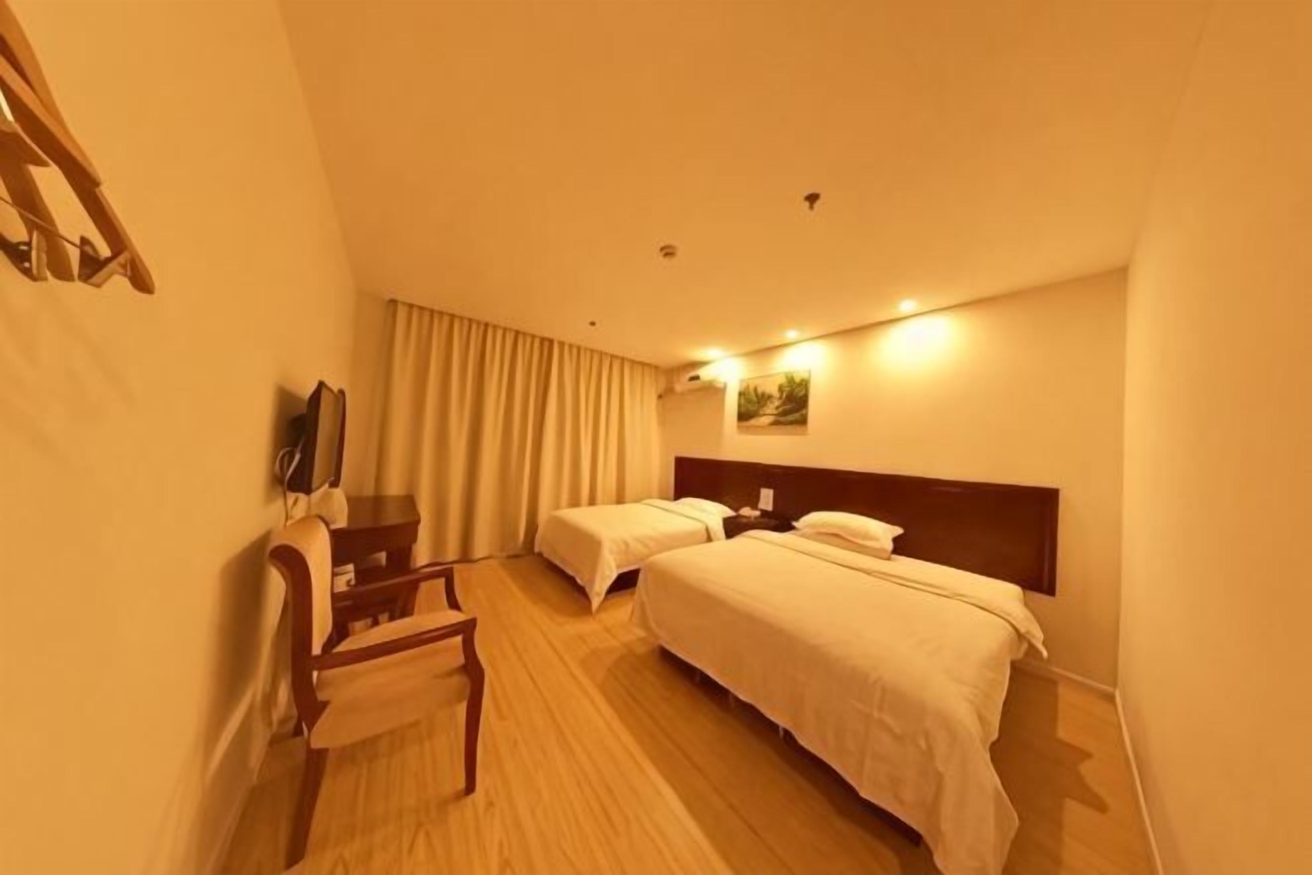A hotel room with two beds, a desk, a chair, a TV, and a curtain.