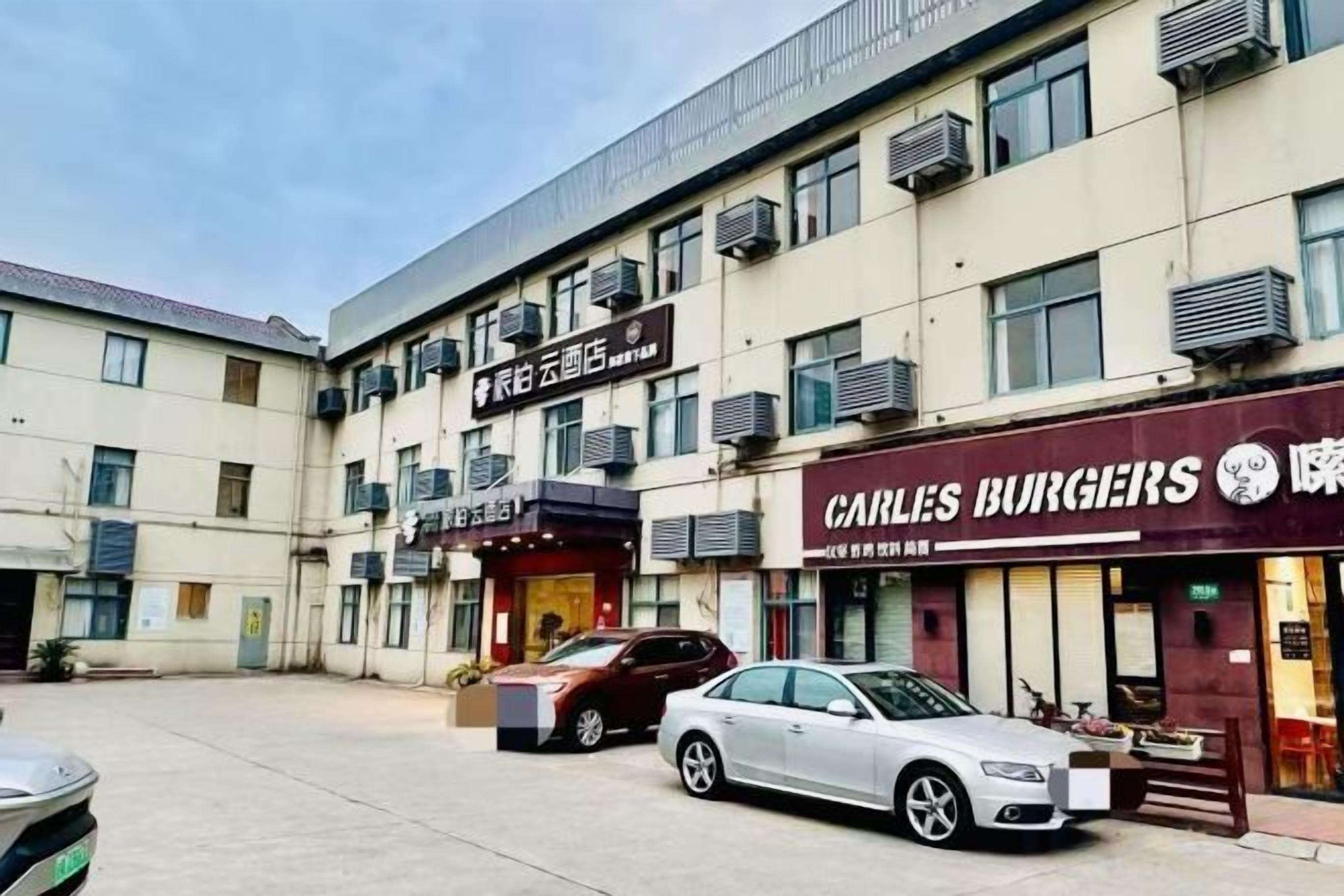 Un immeuble à plusieurs étages dont le rez-de-chaussée abrite des commerces, notamment un restaurant et une entreprise dont l'enseigne est visible.