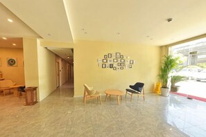 A hotel lobby with a reception desk, seating area, and a wall with framed pictures. - Pebble Motel (Shanghai Beidi Road) (Shanghai)