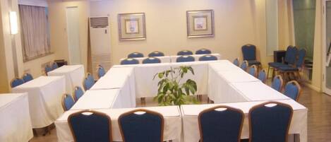 A conference room with a long table, chairs, and a potted plant.