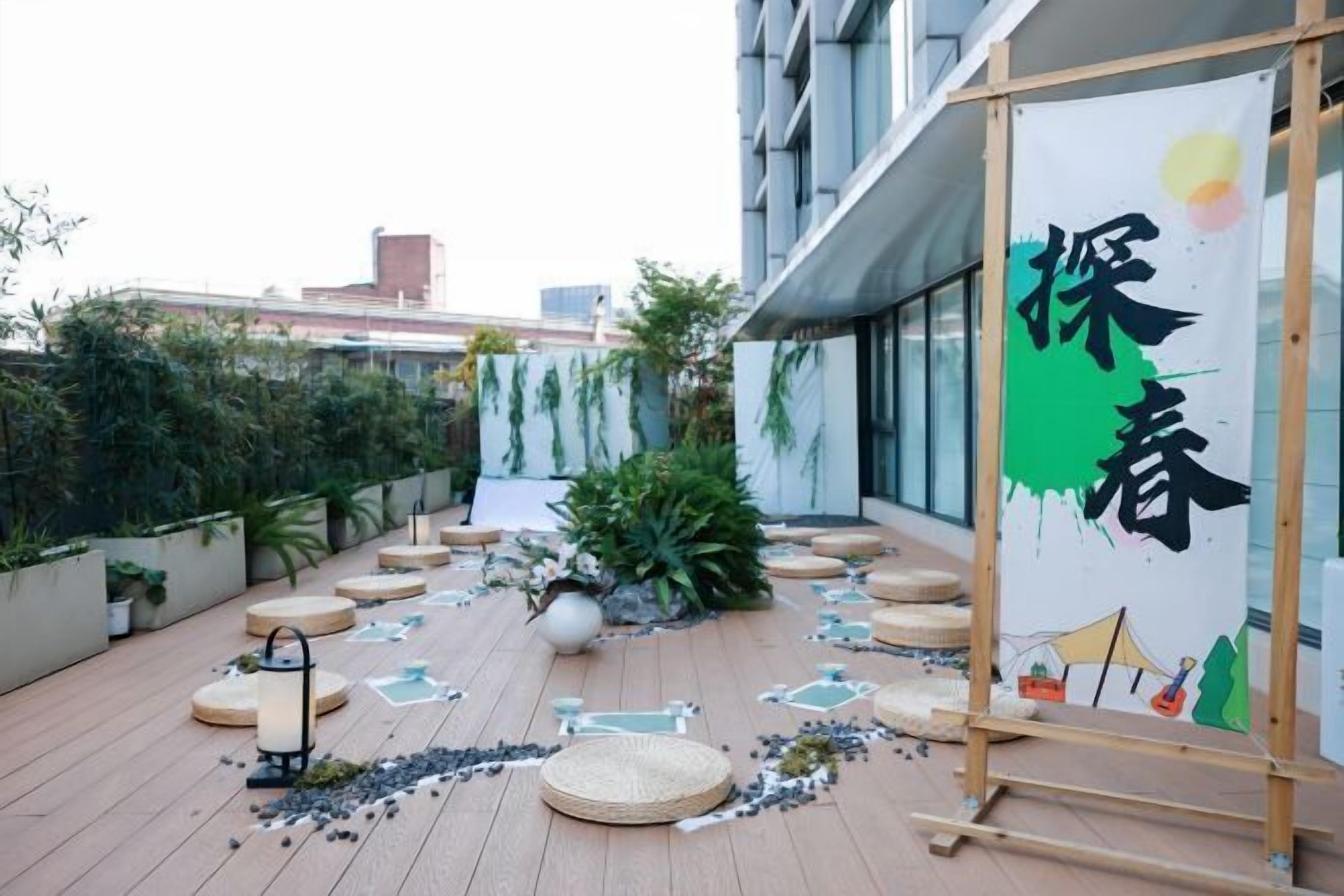 Une terrasse sur le toit, dotée d’une plateforme en bois, de plantes en pot et d’une banderole ornée de caractères chinois.