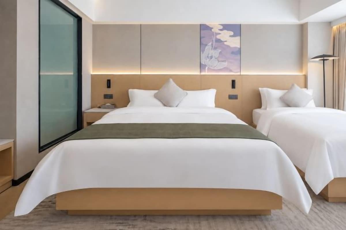 Une chambre d’hôtel avec deux lits, une grande fenêtre et un design moderne.