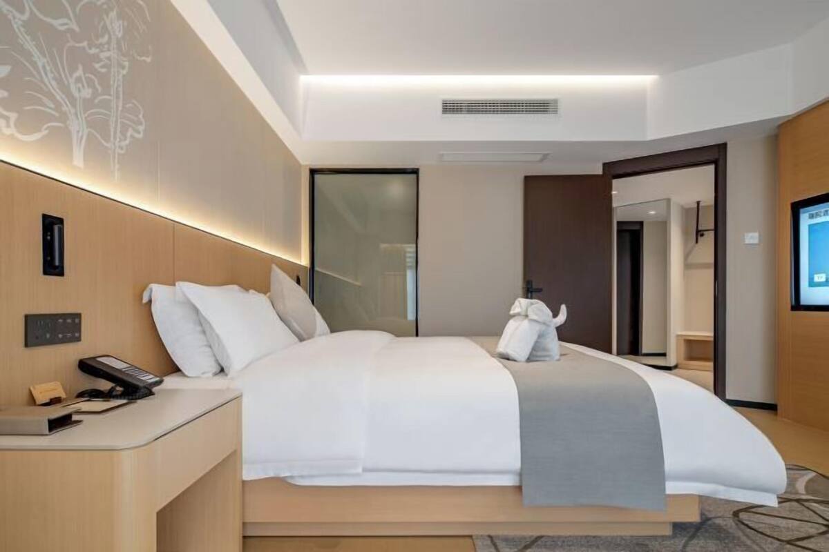A modern hotel room with a bed, bedside table, and a television.