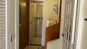 Un pasillo con piso de baldosas, una puerta de madera y una puerta blanca con paneles de vidrio.