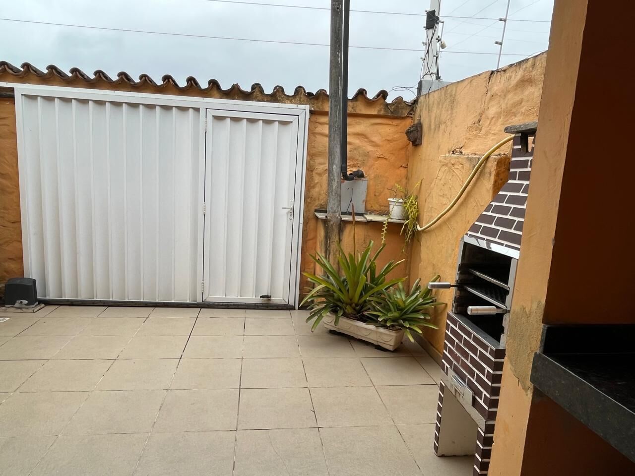 A patio with a white sliding door, a brick oven, and potted plants.
