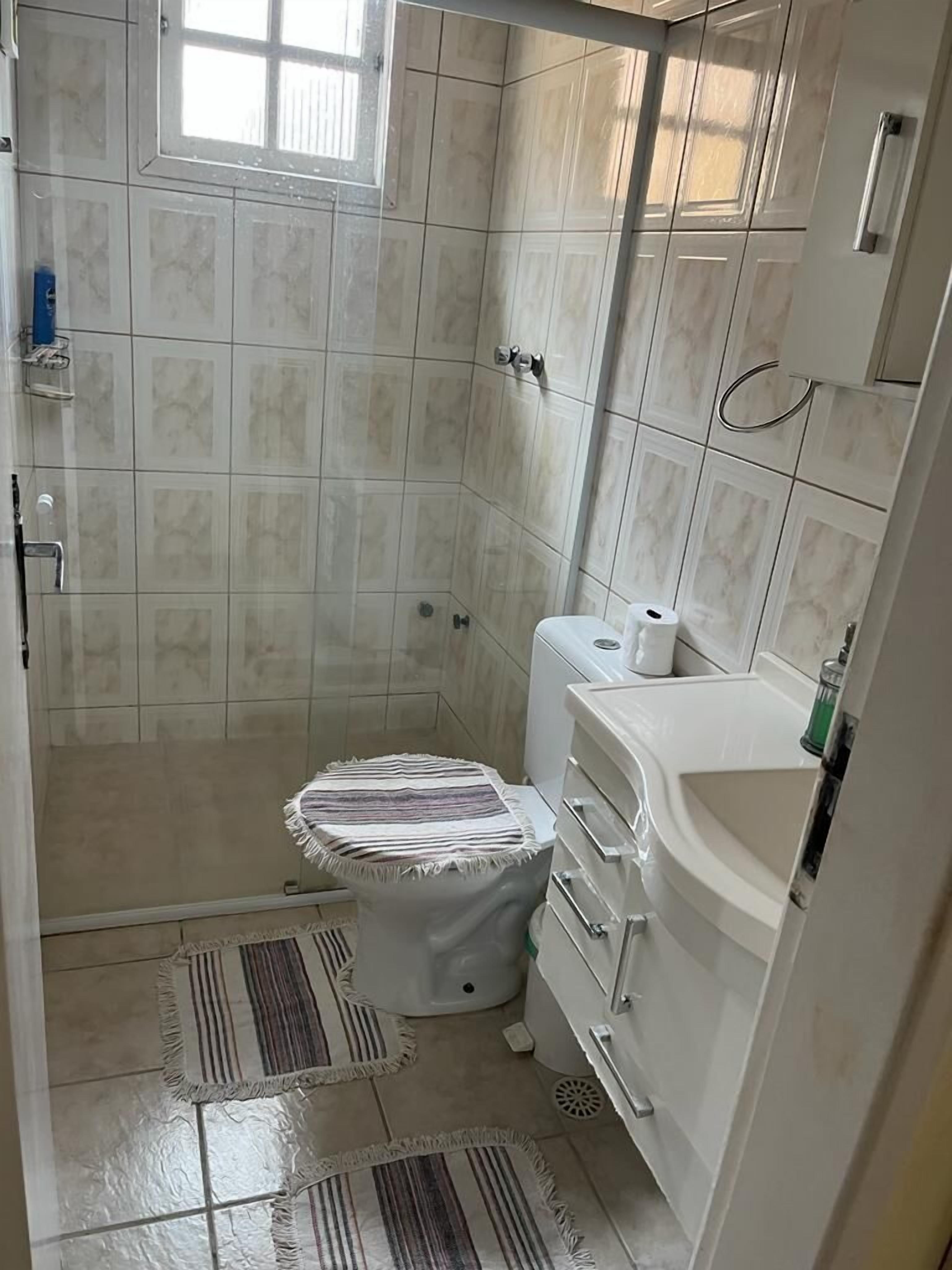 A small bathroom with a shower, toilet, and sink.
