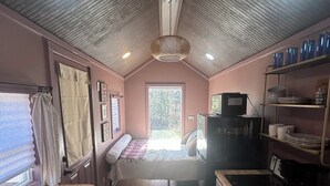 Interior compacto de una caravana con kitchenette, cama y comedor.