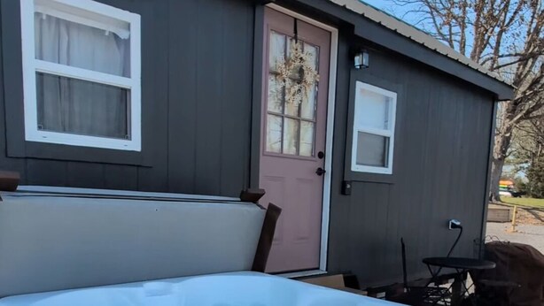 Un jacuzzi frente a una casa con puerta y ventanas.