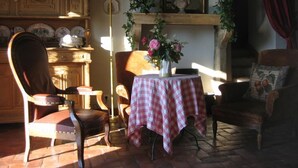 A cozy room with a fireplace, a table with a checkered tablecloth, and a chair. - Le Pré Blanc - CHANGE - Gîte (CHANGE)