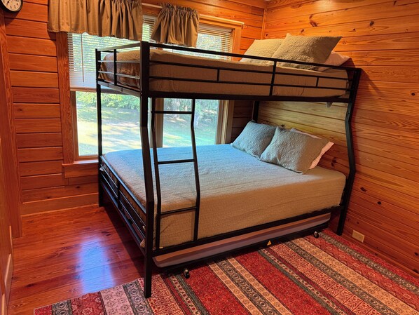 A bunk bed in a wooden cabin room with a window and a patterned rug. - Edisto River Waterfront Cabin in Saint George (Saint George)