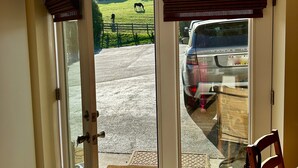 Uma porta com um letreiro 'WELCOME', vista de uma área de estacionamento com um carro e uma cadeira de madeira no interior.