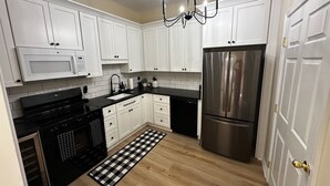 Uma cozinha moderna com armários brancos, eletrodomésticos de aço inoxidável e um tapete quadriculado em preto e branco.