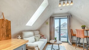 A cozy loft apartment with a loft bed, a small dining area, and a view of the street through a large window. - 2 bedroom accommodation in Narbeth (Narbeth)
