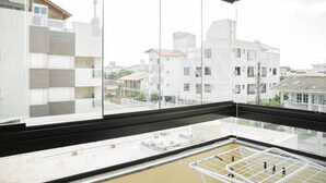 Un apartamento moderno con ventanas amplias, un balcón y vistas de los edificios circundantes.