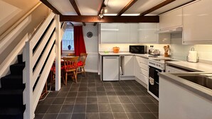 Cocina compacta con armarios blancos, microondas, tostadora y pileta.