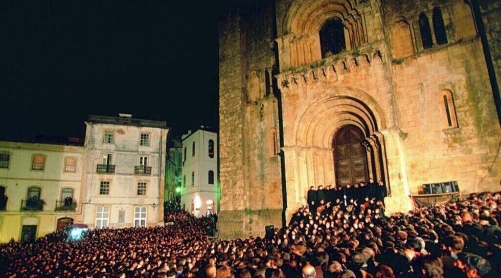 A large crowd gathered in front of a historic building with a prominent archway.