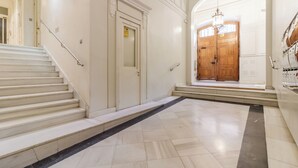 A grand hallway with a marble floor, a wooden door, and a staircase. - Justicia by Wynwood House (Madrid)