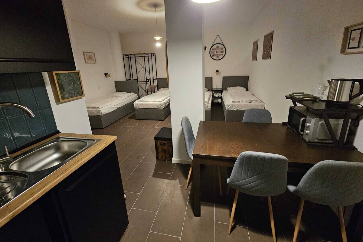Habitació d'hotel compacta amb bugateria, dos llits individuals, zona de menjador amb taula i cadires, i bany petit.