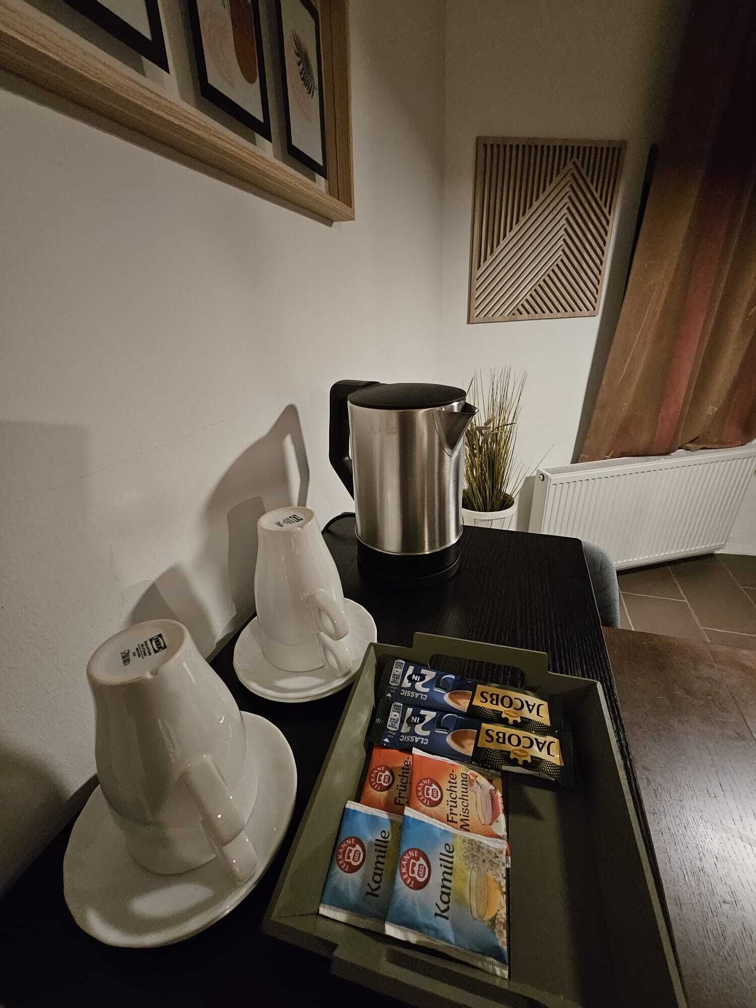 A kitchen area with a coffee maker, two white cups, and a tray with coffee pods.