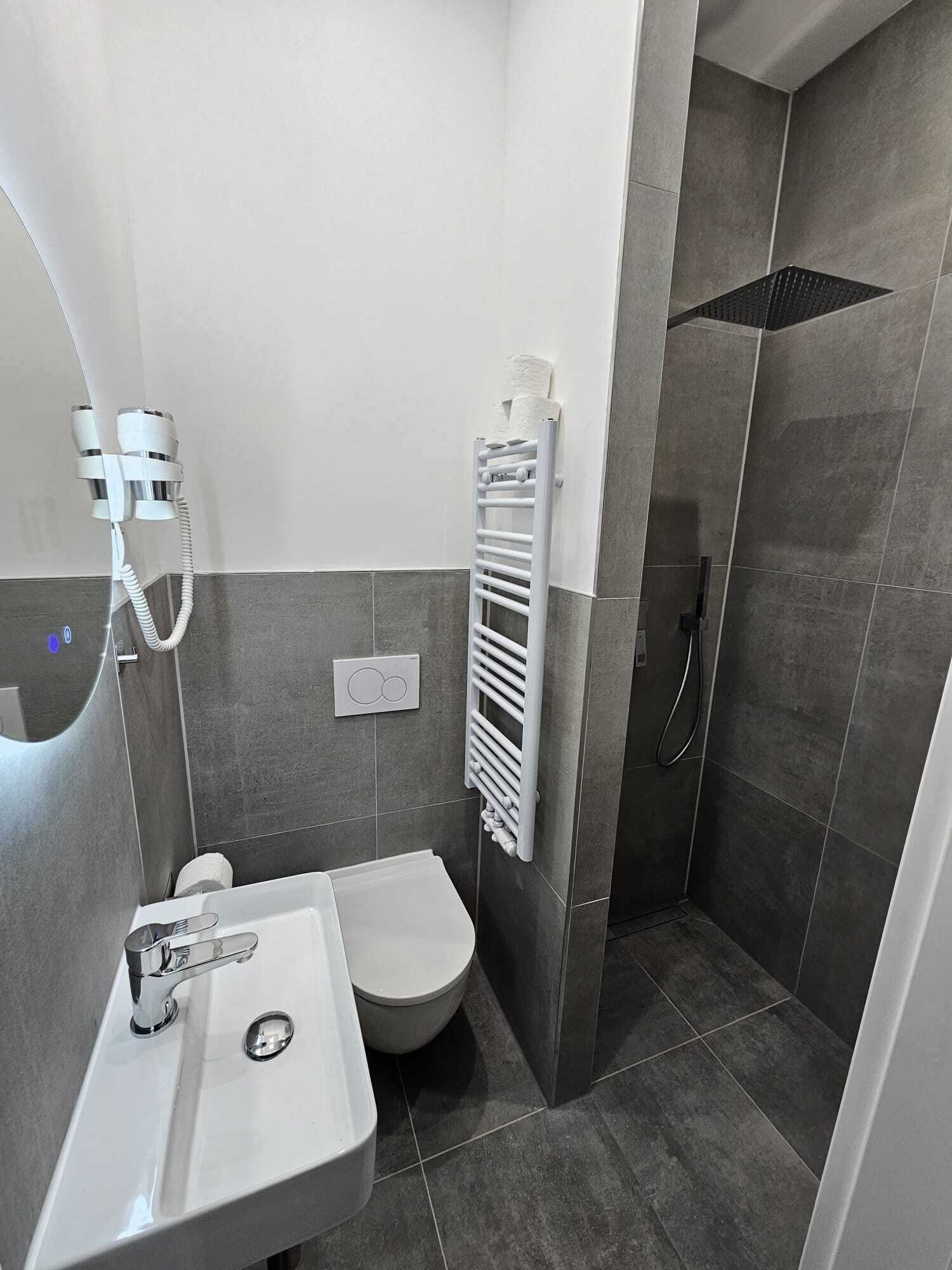Une salle de bain moderne avec un lavabo blanc, des toilettes et une douche à l’italienne.