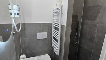 Une salle de bain moderne avec un lavabo blanc, des toilettes et une douche à l’italienne.