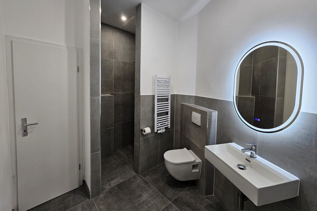 Une salle de bain moderne équipée de toilettes, d’un lavabo et d’une zone douche.