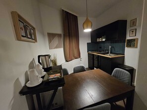 Cozy living space with a dining area and kitchenette, featuring a wooden table and chairs, coffee station, and sink.