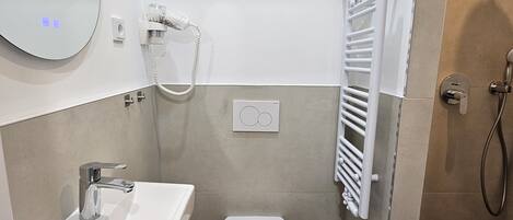 A modern bathroom with a white sink, toilet, and a wall-mounted mirror.