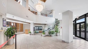 Un hall d’entrée spacieux, agrémenté d’un escalier, de plantes en pot et d’un lustre.