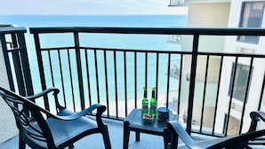 Un balcon avec deux chaises et une table, donnant sur une étendue d’eau.