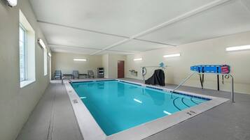 Una piscina con borde de azulejos, una silla de salvavidas y zona de vestuarios.