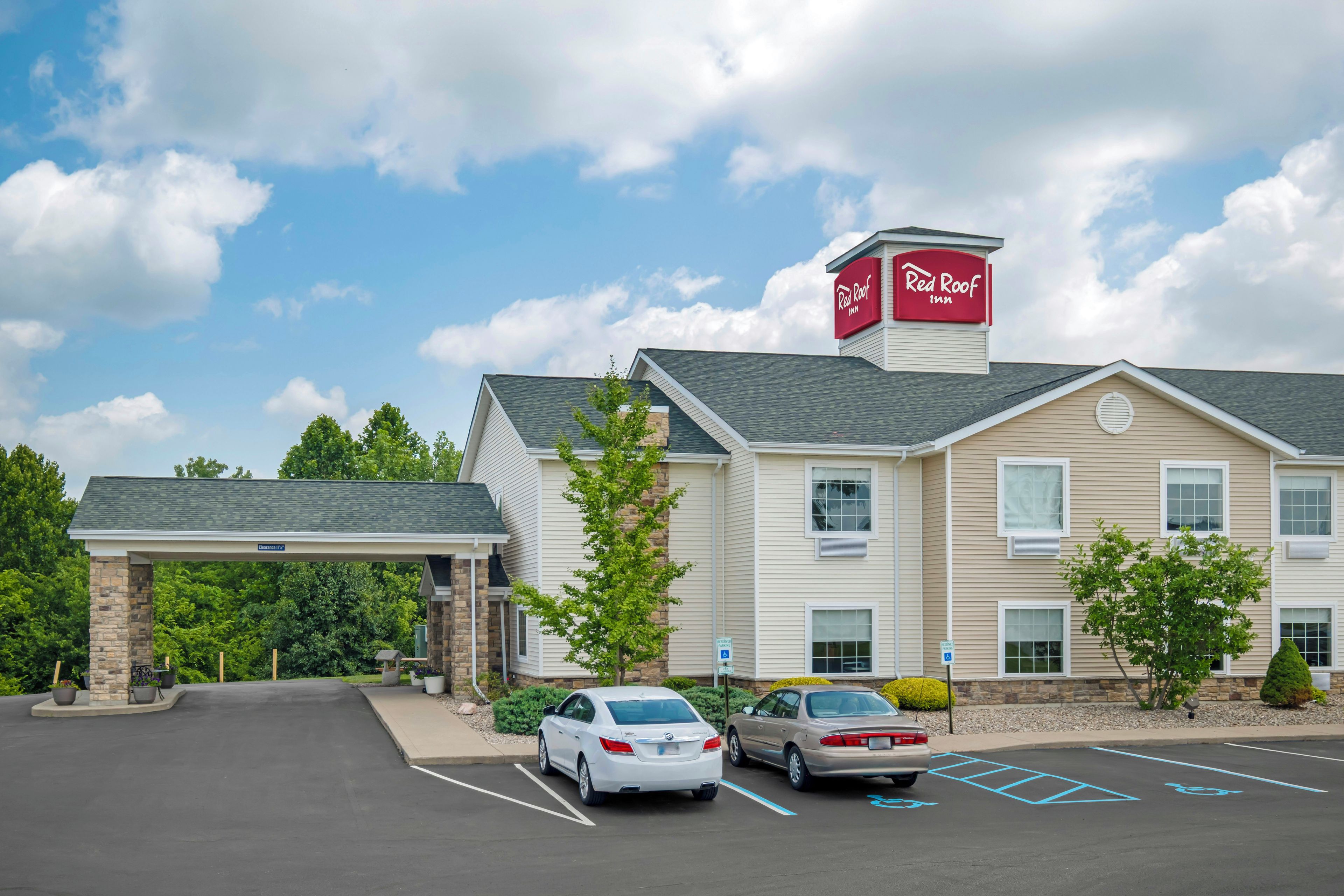 Un hôtel Red Roof Inn doté d’un parking, de deux voitures et d’une entrée abritée.