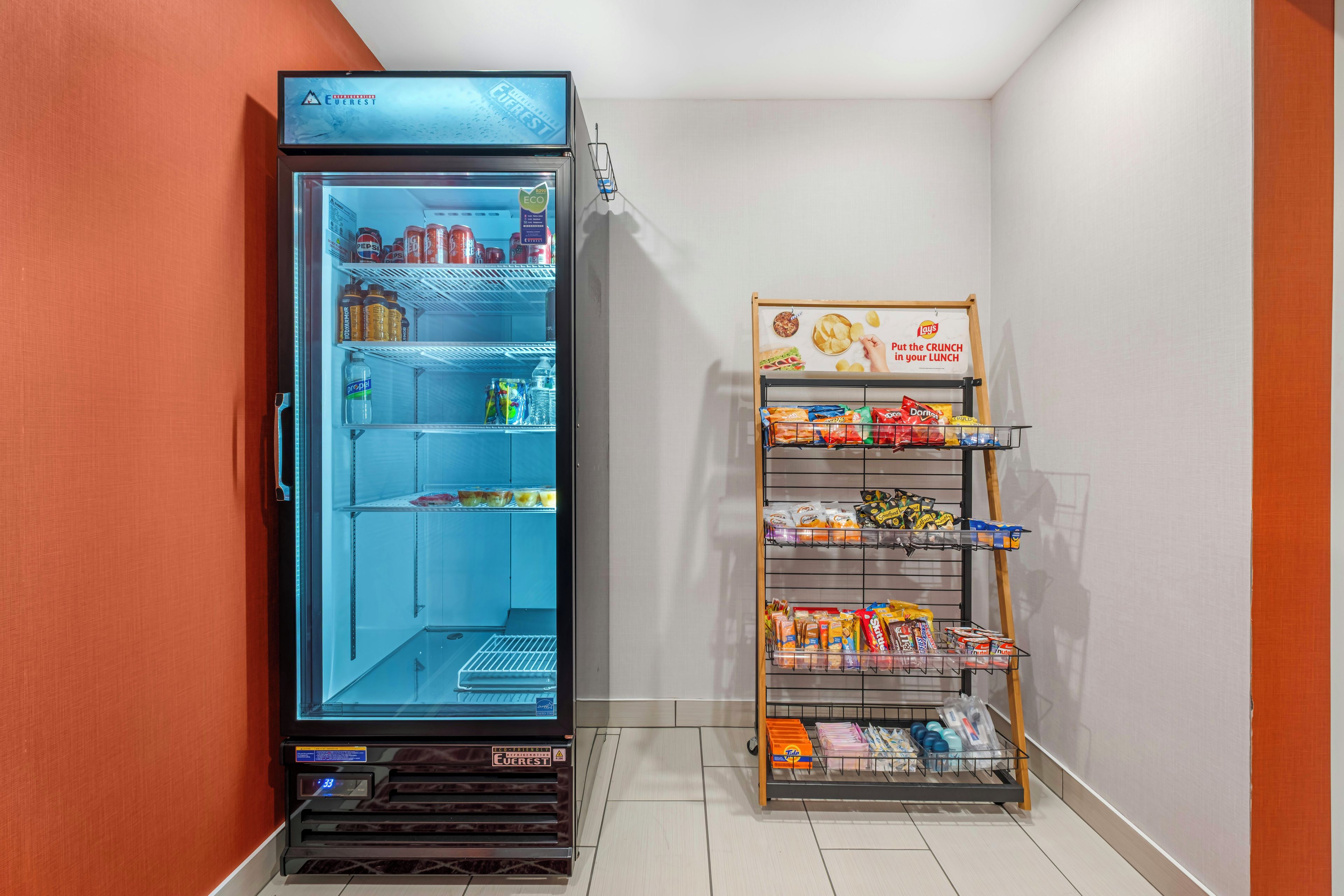 Eine Minibar mit Kühlschrank und einem Regal voller Snacks und Getränke.