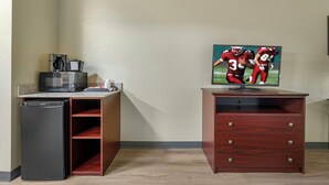 A room with a kitchenette, a flat-screen TV mounted on a wooden cabinet, and a wall-mounted television displaying a sports game. - Red Roof Inn Charlestown (Charlestown)