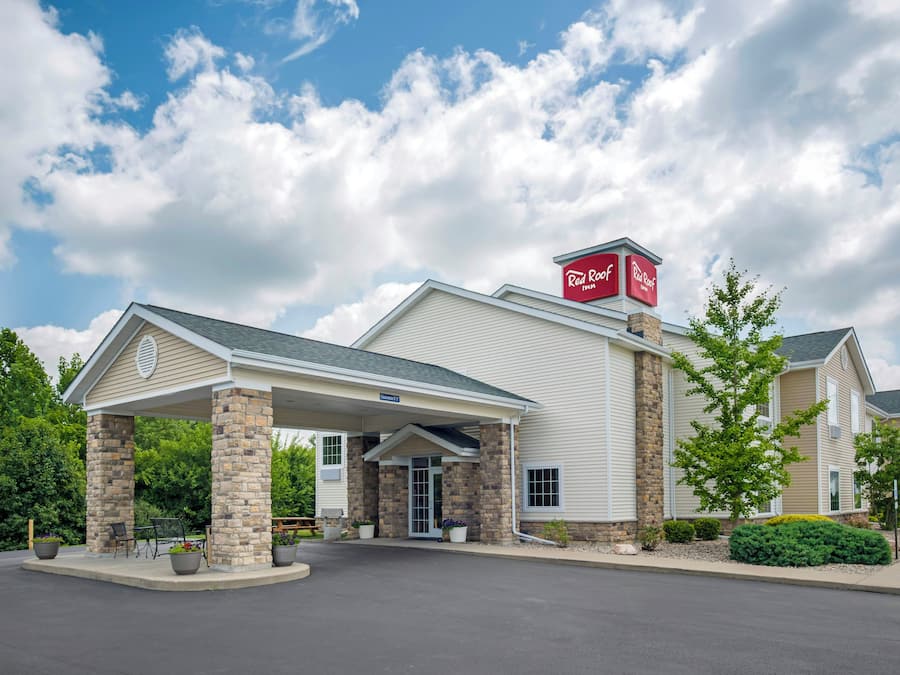 A Red Roof Inn with a covered entrance, stone pillars, and a clear sky.