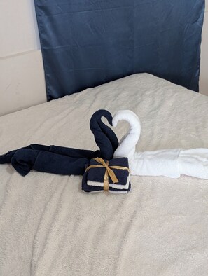 A bed with a beige blanket and two towels, one black and one white, tied with a gold ribbon. - B'lu Bamboo - GH.A.RB (Moalboal)