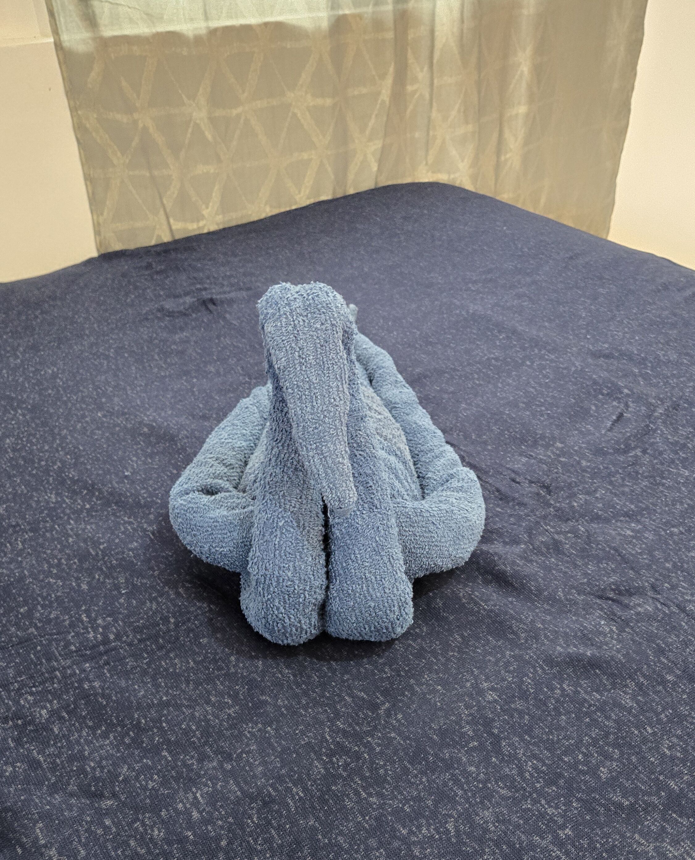 A dark blue textured sofa in a room with a patterned curtain in the background.