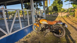 Uma motocicleta estacionada perto de uma estrutura azul com estrutura metálica.