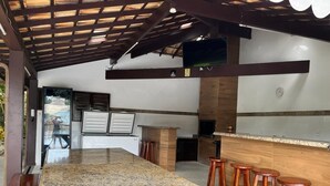 Una cocina amplia con encimera de granito, taburetes de madera y estructura de techo de madera.