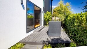 Ein modernes Gebäude mit einer großen Glasbeschwerung, einer Holzterrasse und einem Korbstuhl.