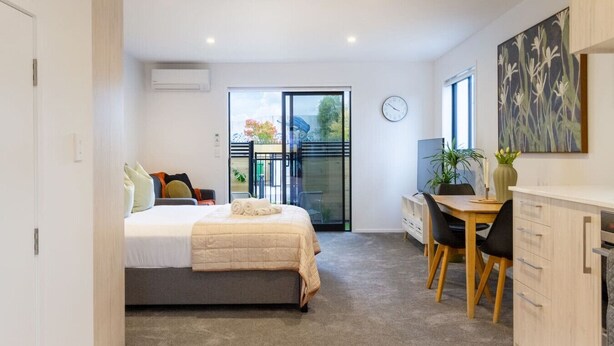 Una habitación de hotel compacta con cama, escritorio y zona de comedor.