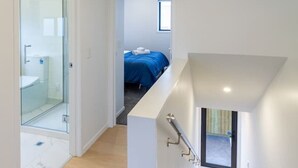 Een modern interieur met een trap naar een slaapkamer met een blauwe sprei.