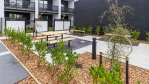 A courtyard with outdoor seating, a black wall, and a building with balconies.