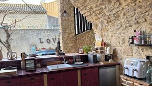 Una cocina rústica con paredes de piedra, una mesa de madera y un lavamanos empotrado.