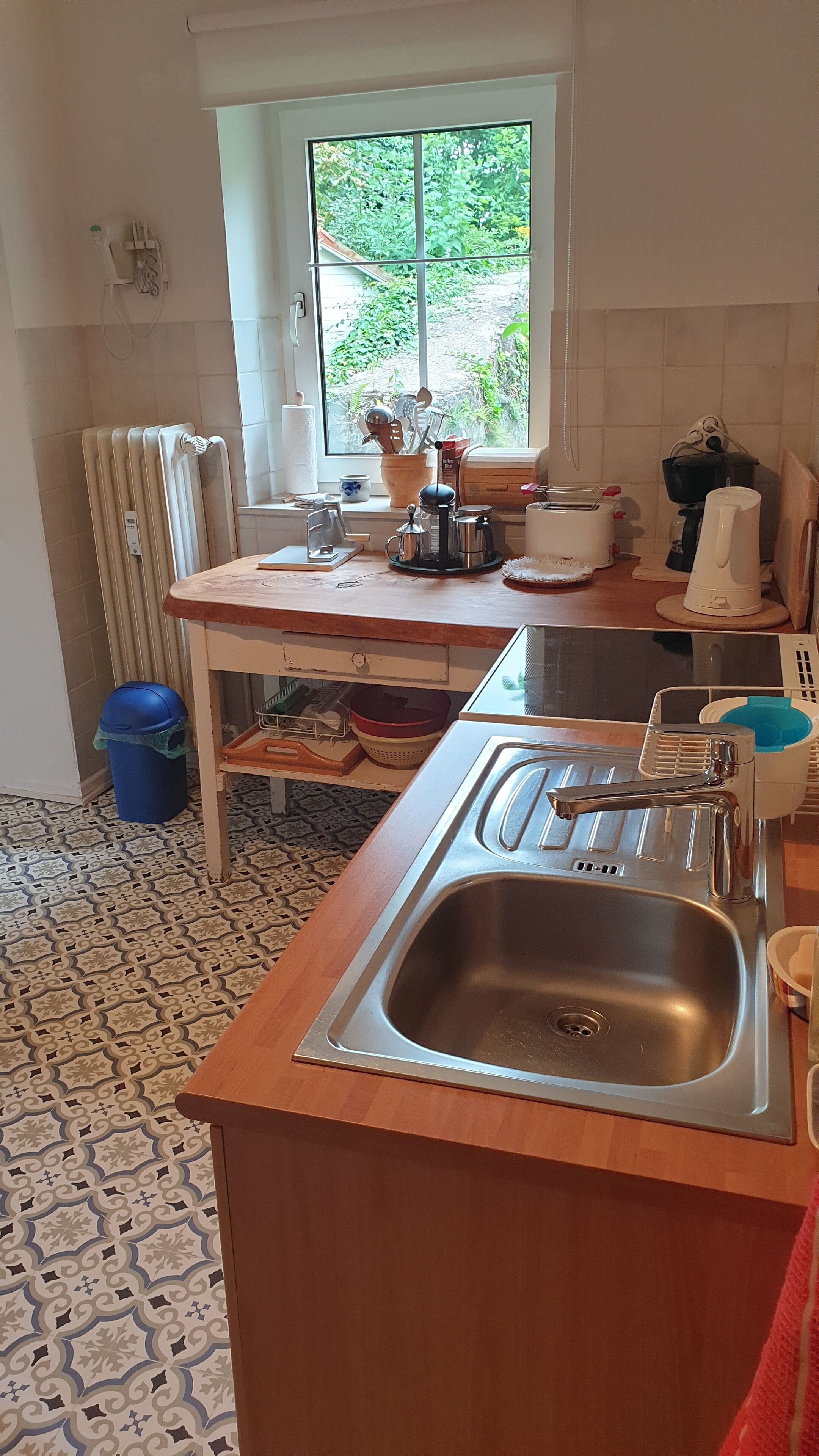 A compact kitchen with a window, a sink, and various kitchen appliances.