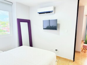 Camera d'albergo con un letto, una televisione a muro, un condizionatore d'aria e vista sull'esterno.