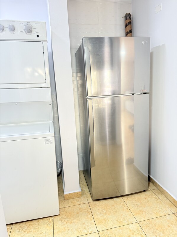 Une cuisine de taille réduite, dotée d’un réfrigérateur en acier inoxydable et d’un lave-linge blanc.