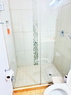 Un bagno moderno con doccia vetrata, piastrelle bianche e un water.