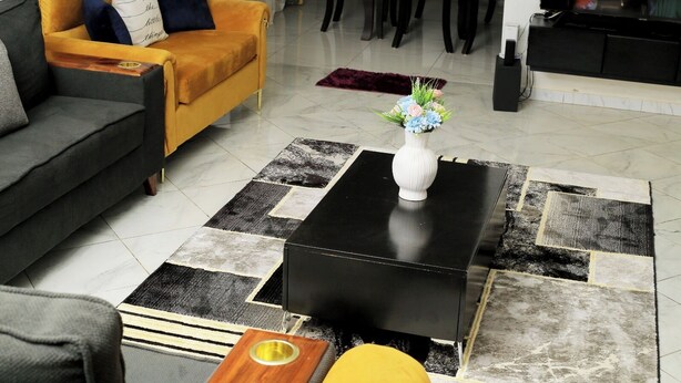 Ein Wohnzimmer mit einer Couch, einem Couchtisch und einem Essbereich im Hintergrund.
